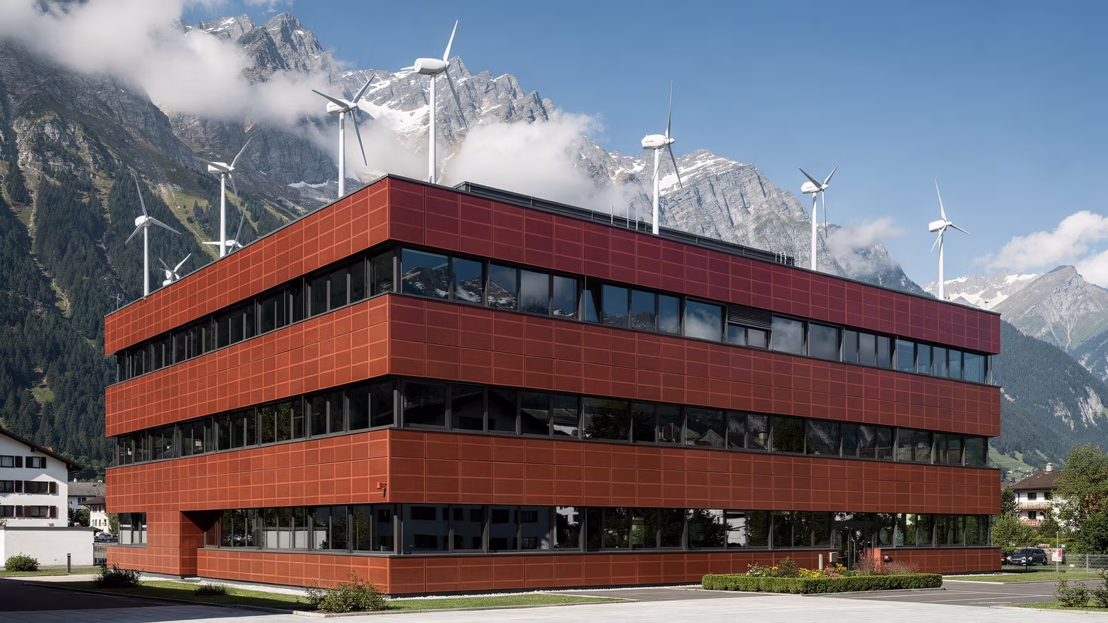 Bürogebäude mit Photovoltaik auf dem Dach vor einer Bergkulisse mit Windrädern